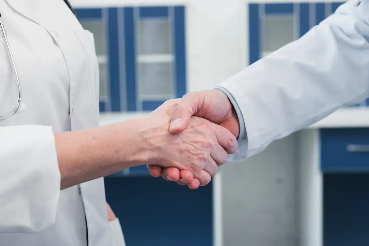 Two clinicians in white coats shaking hands
