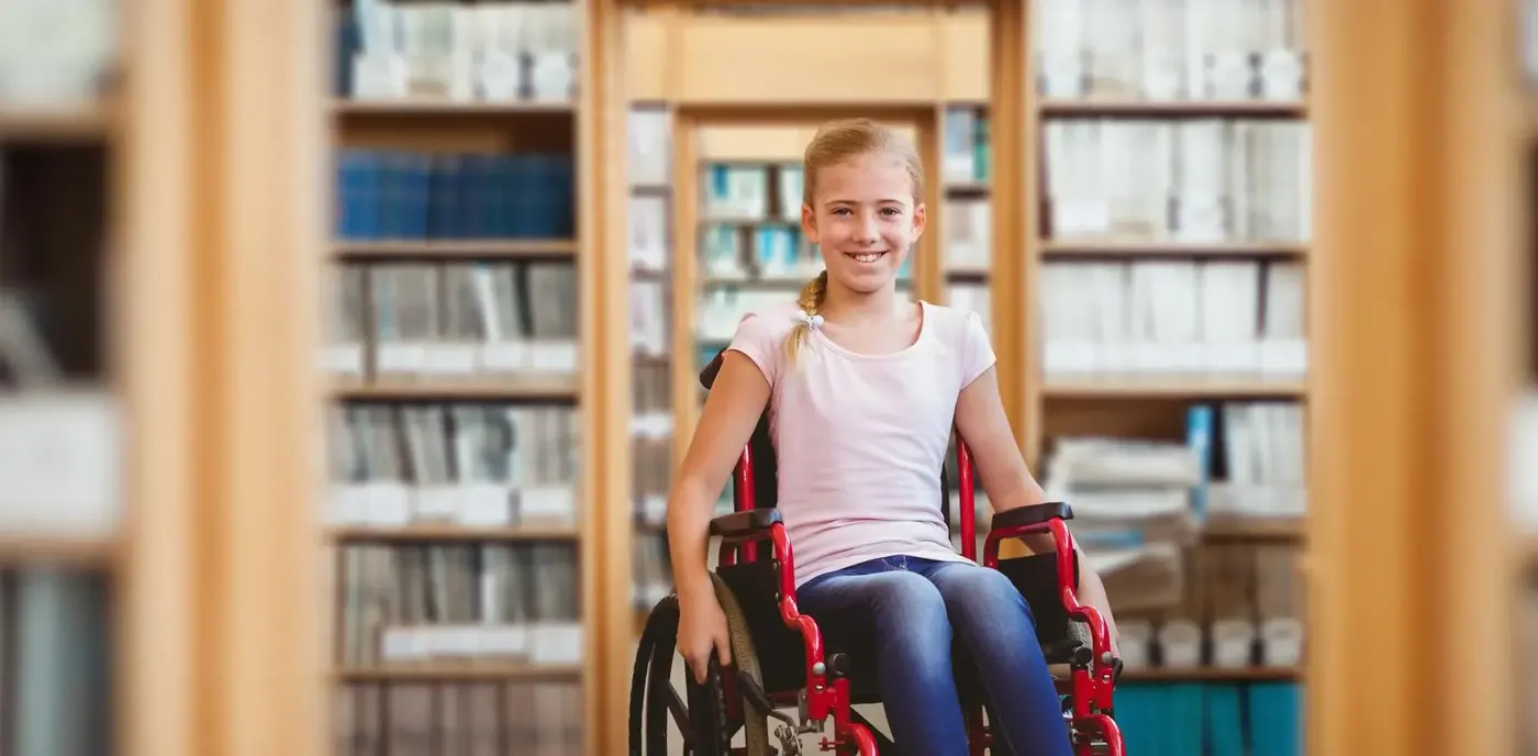 Girl in a wheelchair in front of bookshelves
