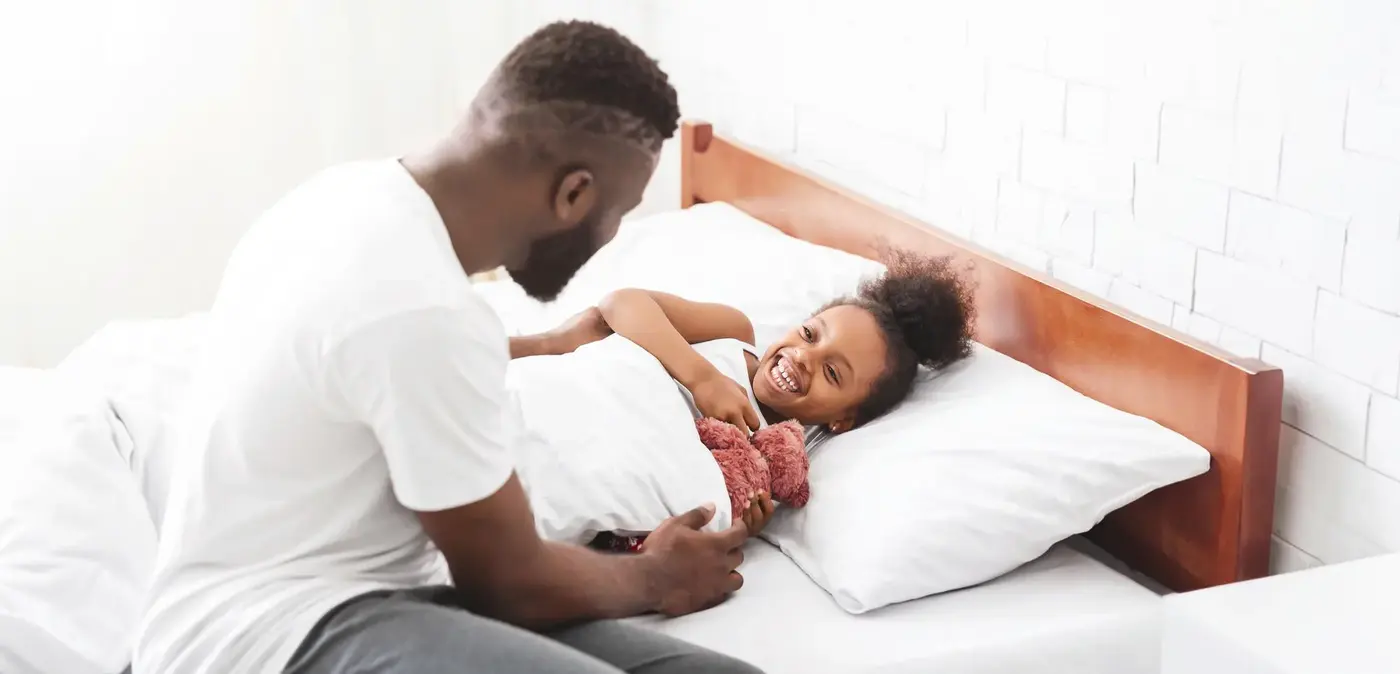 Father sitting on the bed with his smiling daughter