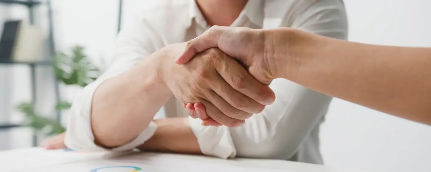 Two people shaking hands across a table