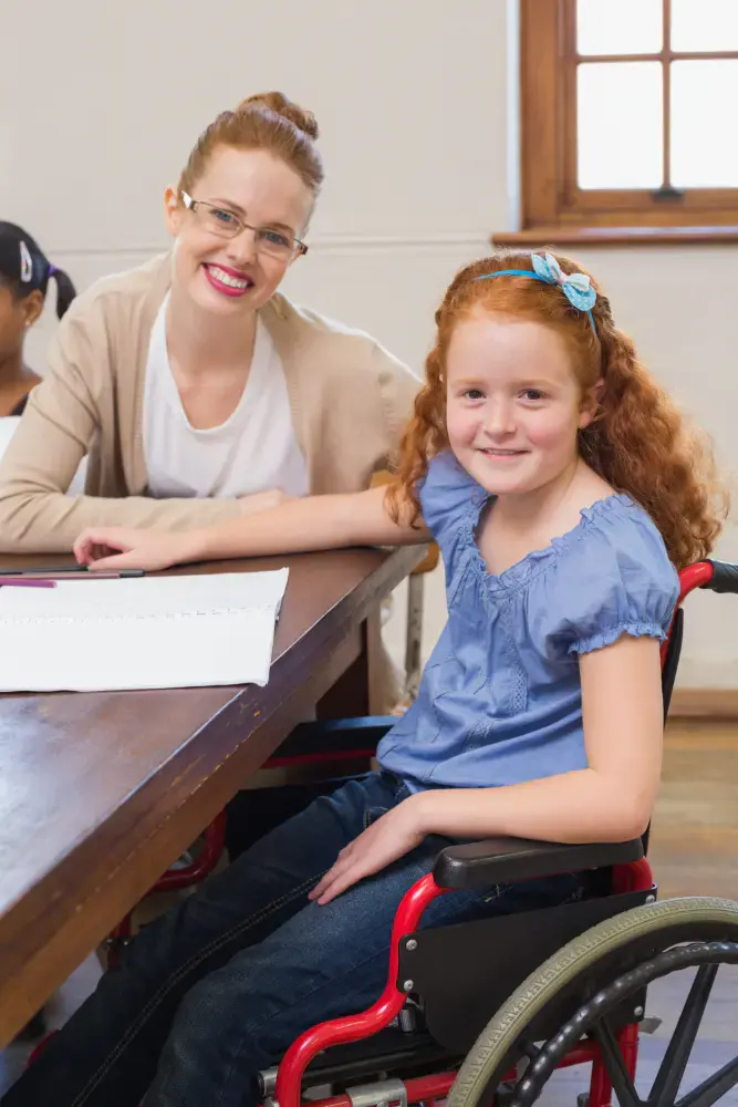 Girl in a wheelchair at a table with an adult beside her